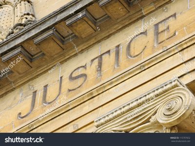 The word Justice inscribed on the exterior of a stone building.