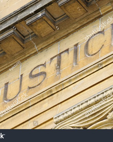 The word Justice inscribed on the exterior of a stone building.
